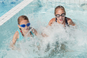 Two happy children playing on the swimming pool at the day time.